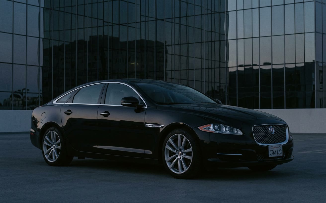 Fekete Jaguar XJ (X351) modern üvegépület előtt, alkonyatkor